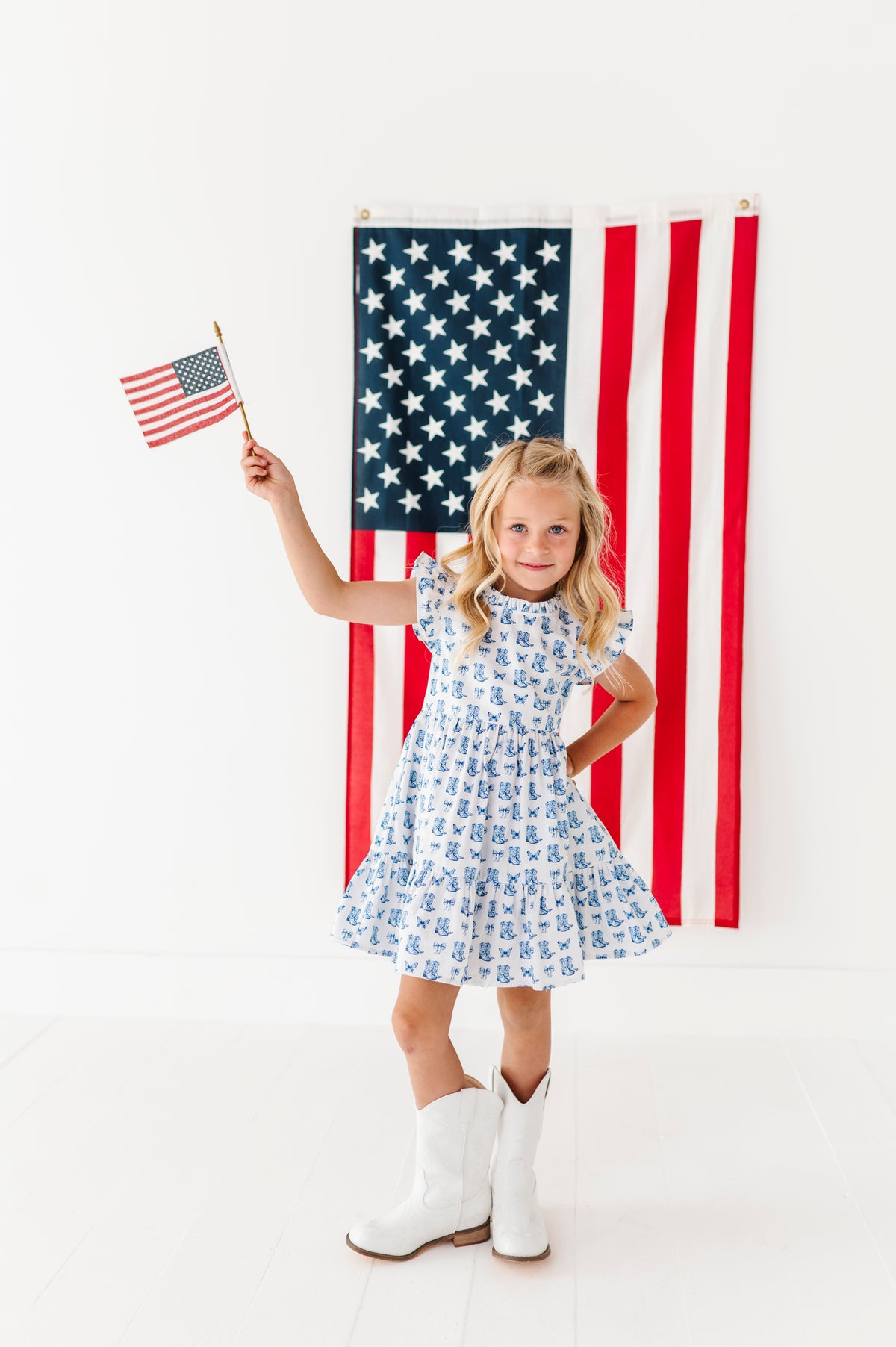 Young girl holding an American flag in front of a large American flag on a white background