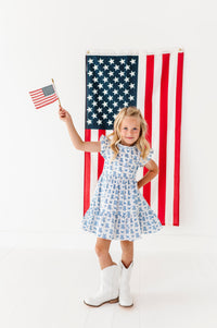 Young girl holding an American flag in front of a large American flag on a white background