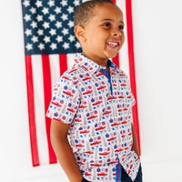 Child wearing a patriotic printed shirt with an American flag in the background