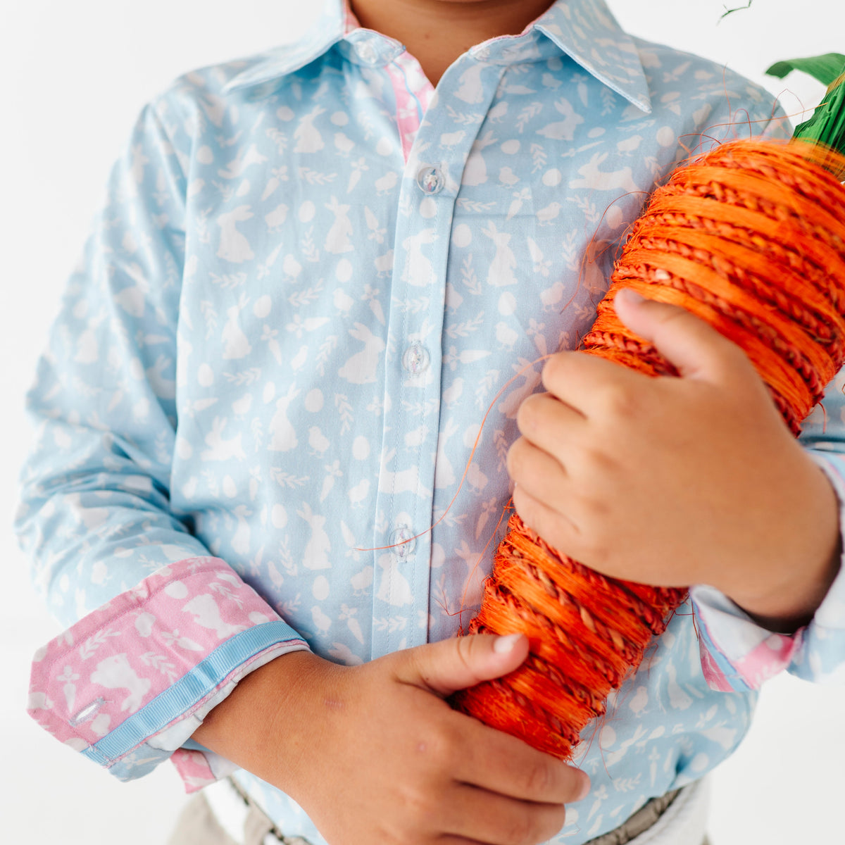 Child holding a large decorative carrot against a white background