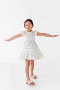 Young girl wearing a white dress with a floral pattern on a white background