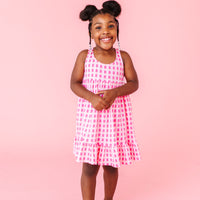 Young girl in a pink popsicle dress standing against a pink background