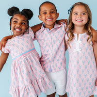 Three children wearing matching pink lobster outfits with a blue background