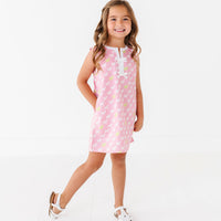 Young girl wearing a pink dress with white puppies on a white background