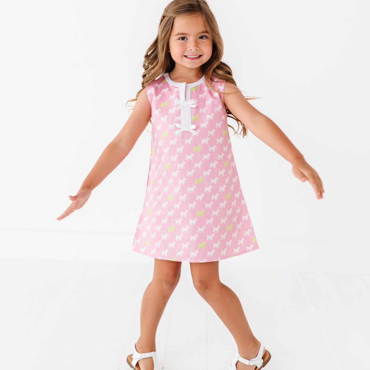 Young girl wearing a pink dress with white puppies on a white background