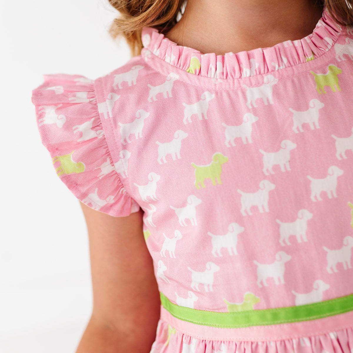 A young girl in a pink dress with a puppy print