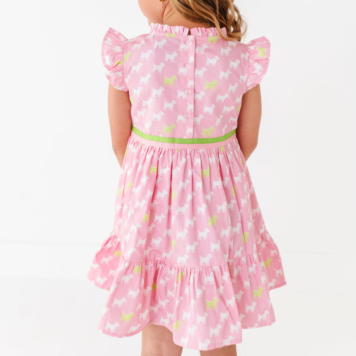 A young girl in a pink dress with a puppy print