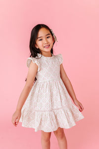 Young girl wearing a white lace dress against a pink background