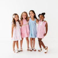 Four young girls wearing matching dresses on a white background